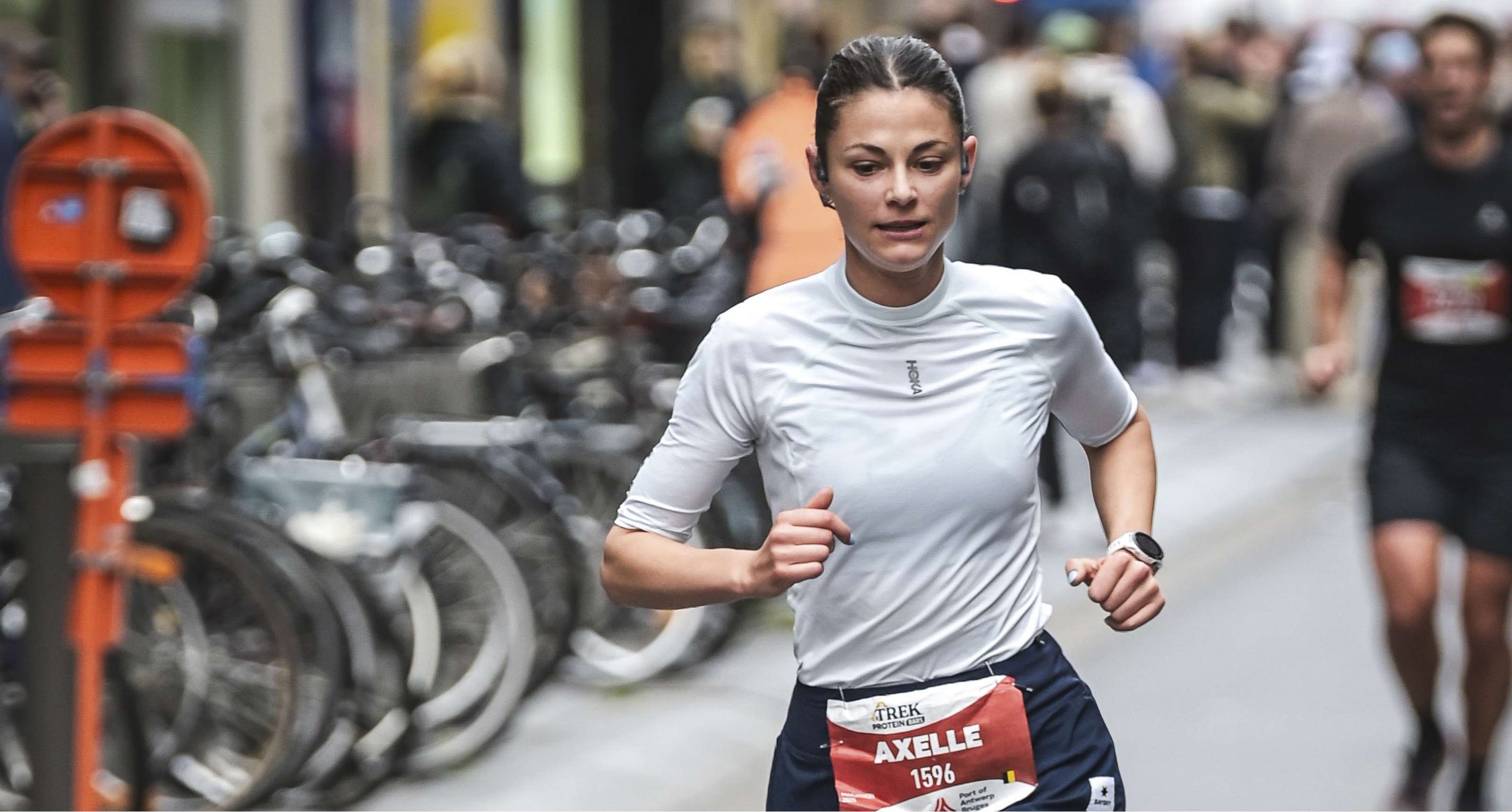 Hardloper Axelle rent geconcentreerd door een stedelijke straat tijdens een wedstrijd.