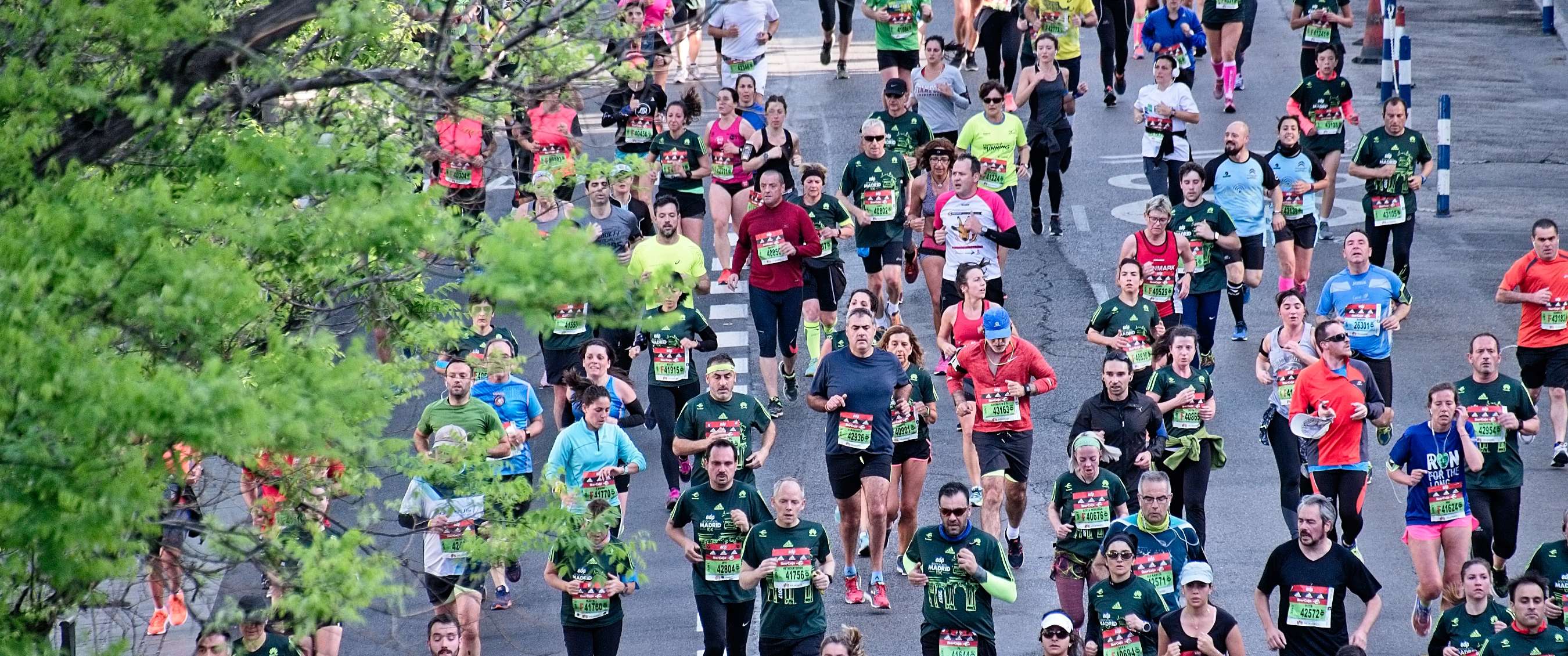 Des coureurs de marathon en tenues variées courent ensemble sur un parcours urbain, vus d’en haut