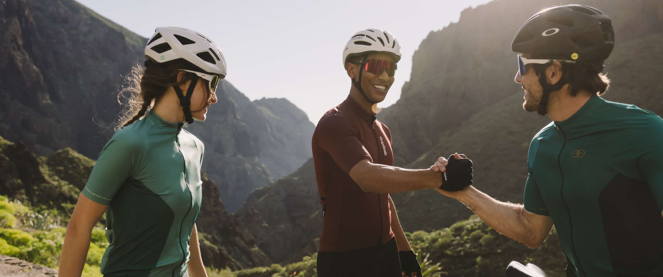 Fietsers met sportbrillen en helmen staan samen op een zonnige bergweg