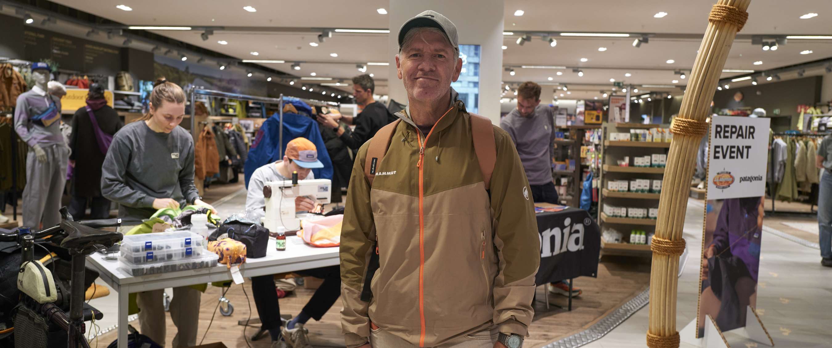 Man staat in een winkelruimte met reparatietafel en zichtbaar bord REPAIR EVENT.