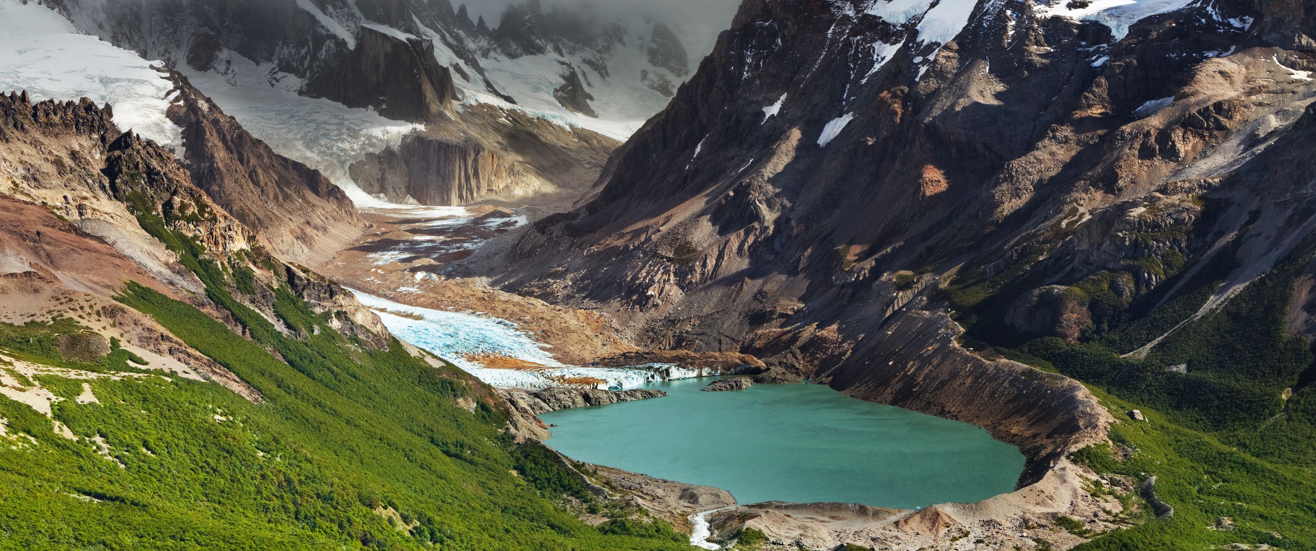 Uitzicht op gletsjermeer aan de voet van besneeuwde bergtoppen.