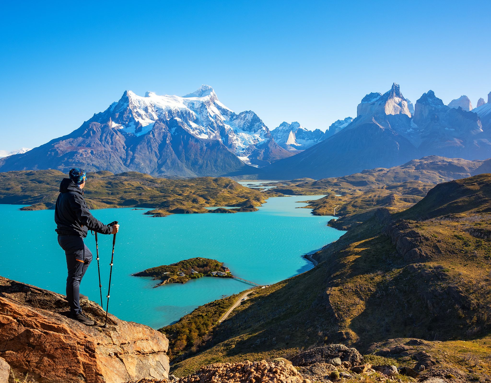 Hiker met uitrusting overziet bergvallei met glinsterend gletsjermeer.