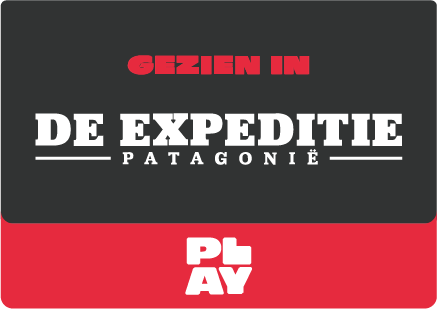 Hiker met uitrusting overziet bergvallei met glinsterend gletsjermeer.