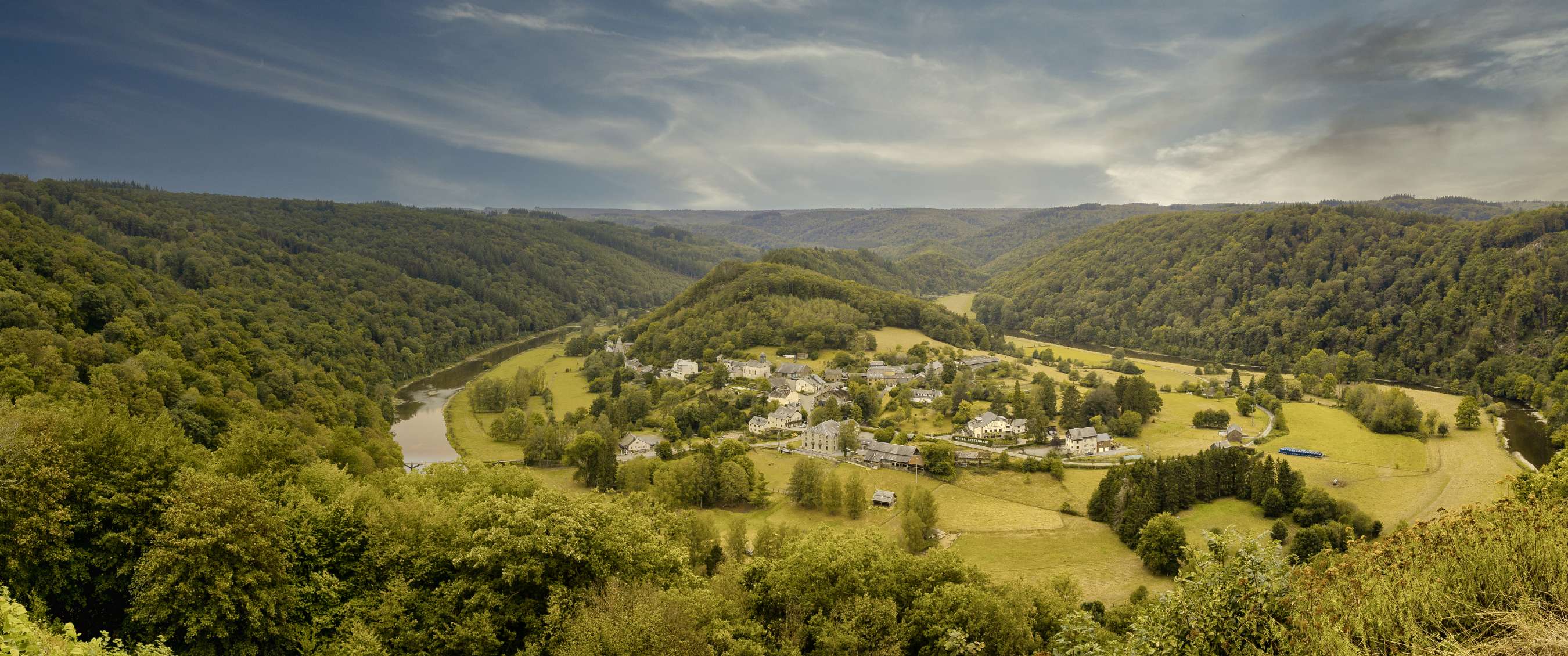 Panoramisch uitzicht op dorp, rivier en beboste heuvels in een groene vallei