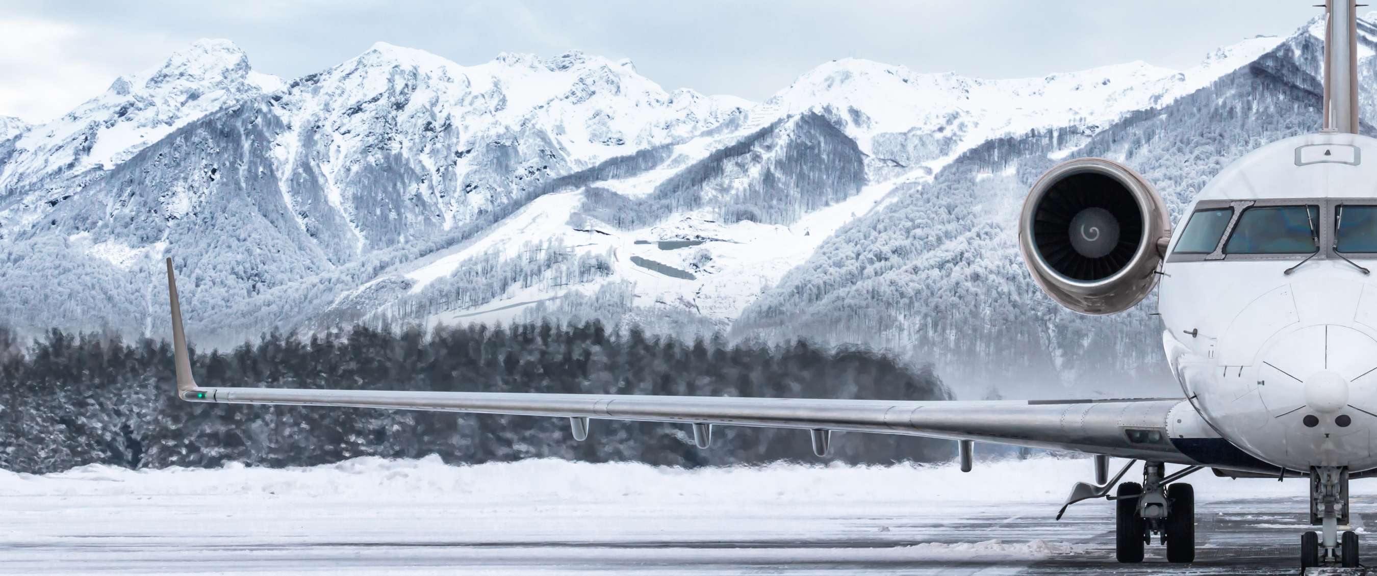 Avion sur une piste enneigée avec des montagnes en arrière-plan.